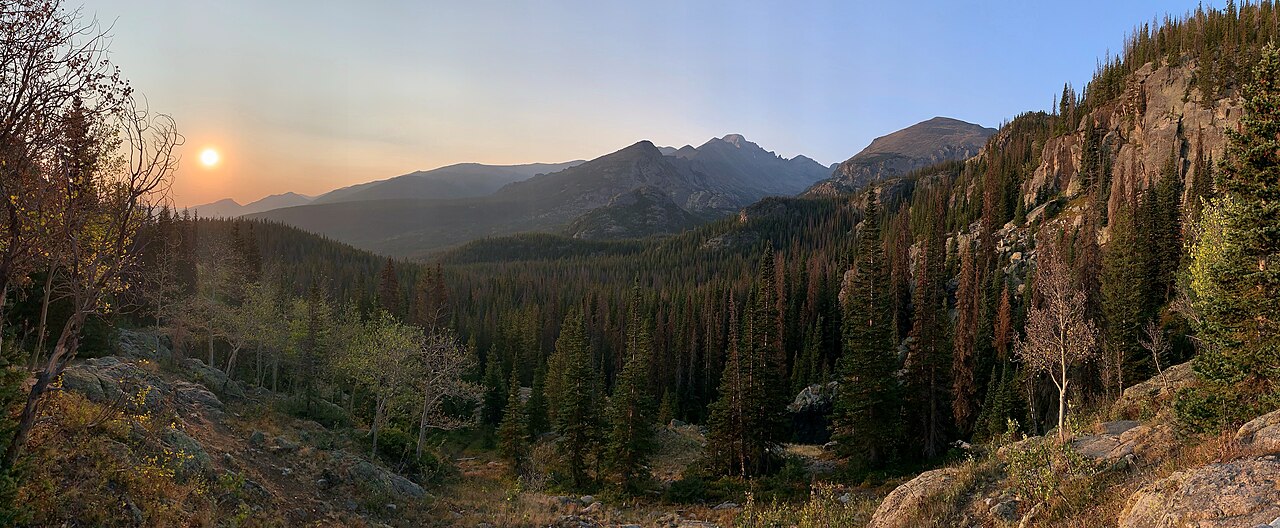 Distant view of distinctive flat-topped Longs Peak (14,259 ft), the highest point in Rocky Mountain National Park, as seen from a rocky overlook along the trail to Dream Lake, at sunrise. Peaks to the